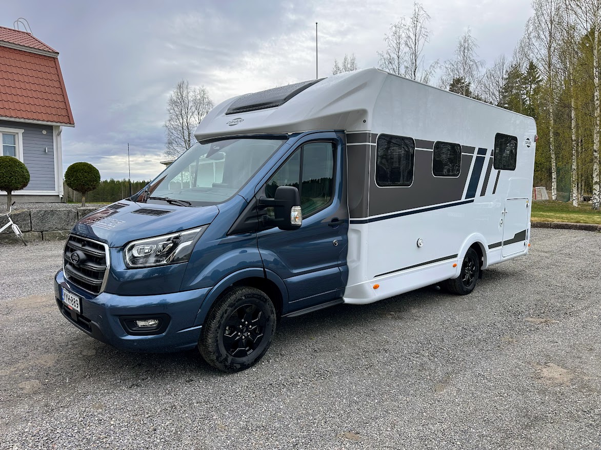 Carado T 449 Edition — sininen Ford Transit -alusta ja valkoinen puoli-integroitu asuinosa etuvasemmalta kuvattuna
